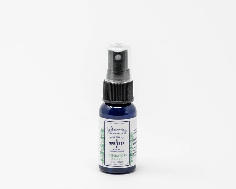 A small blue bottle of BC Essentials eucalyptus essential oil respiratory spritzer with a black spray nozzle, isolated on a white background.
