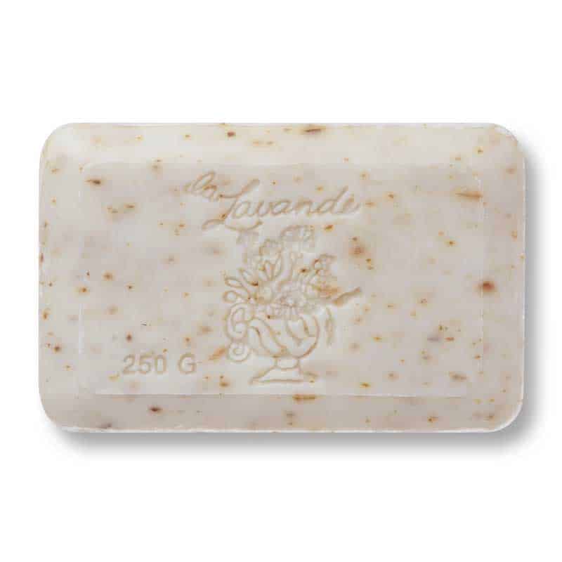 A rectangular bar of La Lavande Milk & Bran French Bath Soap with specks and embossing that reads "la lavande" and illustrates a floral bouquet in a vase, containing moisturizing shea butter, weighing 250 grams.