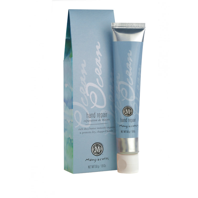 A tube of Mangiacotti Ocean Hand Repair cream beside its corresponding packaging box, both light blue with an ocean wave design, highlighting mango, acai berry, and shea butter ingredients.