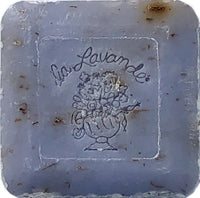 A square fragrant La Lavande Lavender Flower guest soap with embossed text "la lavande" above a floral design etched in white on its smooth surface, captured against a light background.