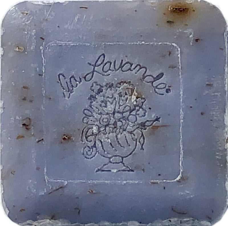 A square-shaped La Lavande Lavender Flower guest soap bar with a floral bouquet design embossed in the center. The soap has flecks of botanicals and a worn, textured appearance.