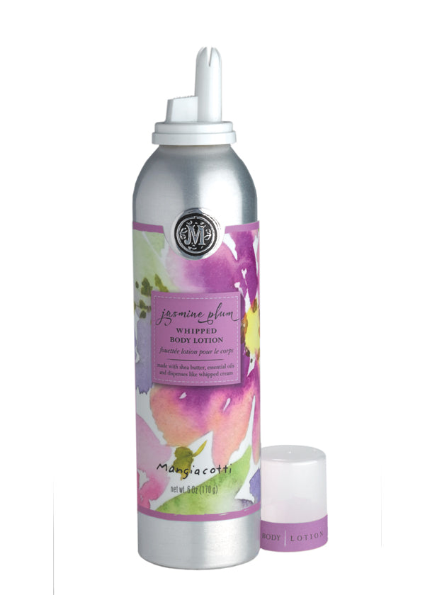 A silver canister of Mangiacotti Jasmine Plum Whipped Body Lotion with shea butter, featuring a floral print label in pink and yellow tones. A small white cap lies in front of the can.