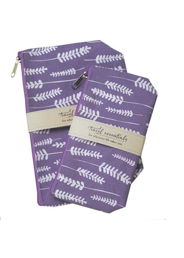 Two Mangiacotti Lavender Travel Essential Cosmetic Bags with white fern patterns, one larger than the other, both secured by a beige elastic band labeled "travel essentials.
