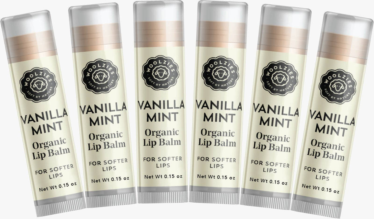 Five tubes of Woolzies Vanilla Mint Lip Balm aligned in a row, with text describing the product as for softer lips. Each tube features a floral emblem and is slightly translucent.
