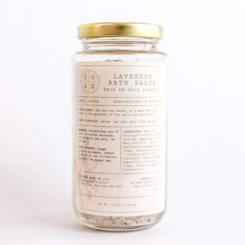 A clear glass jar of SOAK Bath Co. Lavender Bath Salt, featuring a detailed ingredient list and vintage-style label on a plain white background.