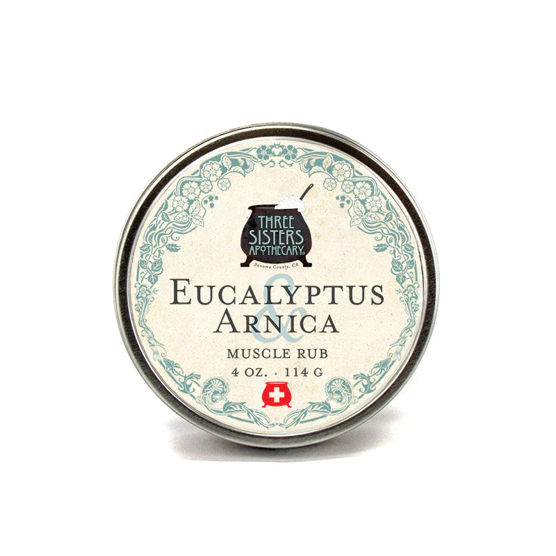A round tin of Three Sisters Apothecary Eucalyptus & Arnica Muscle Rub against a white background. The label is detailed with green ornate designs.