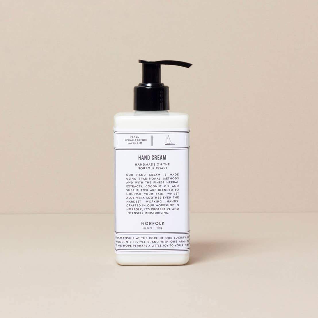 A bottle of moisturizing Norfolk Natural Living Lavender hand lotion with a pump dispenser, against a neutral beige background. The label on the bottle is detailed with text about the product.