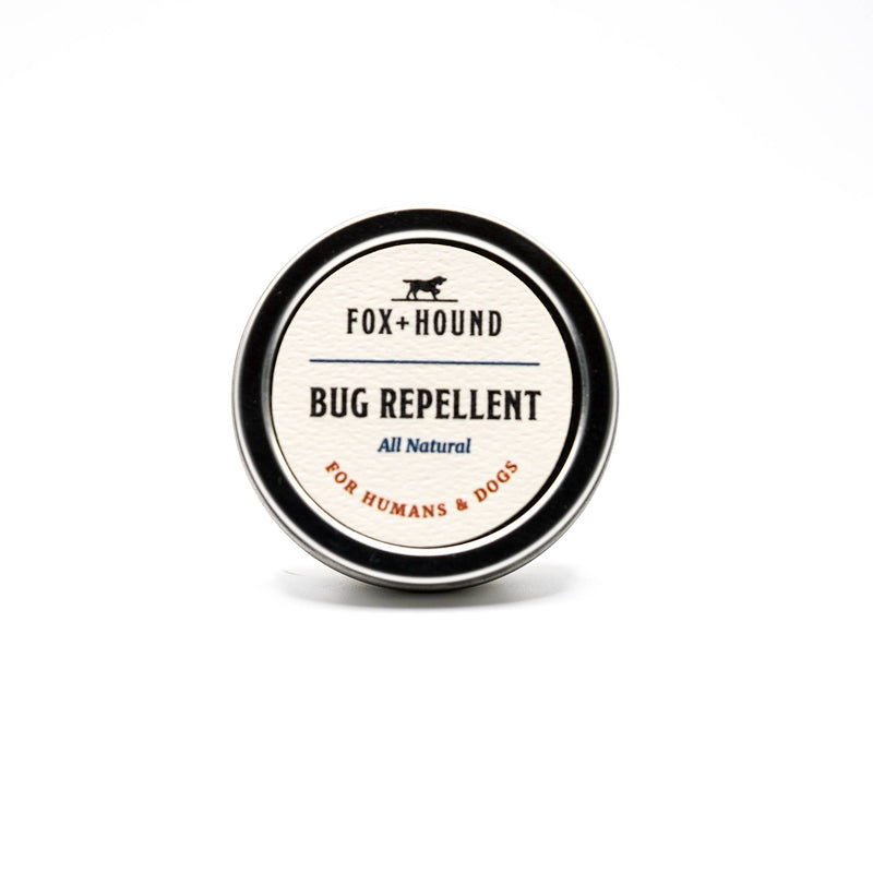 A round tin of Fox + Hound All Natural Solid Bug Insect Repellent Flea Tick Outdoor, marked as all-natural and for both humans and dogs, features a black and white label with text and logo on a white background. Enhanced with