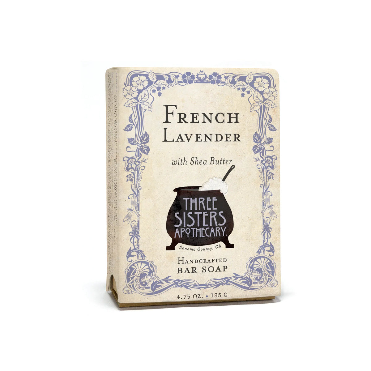 A Three Sisters Apothecary French Lavender Bar Soap with shea butter, featuring elegant floral and scroll designs on its paper packaging.