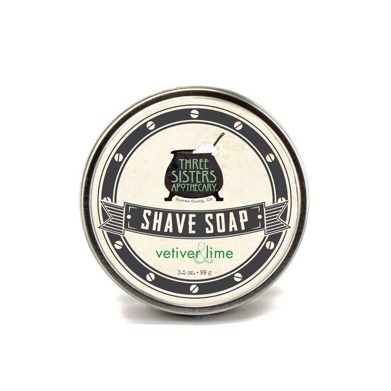 A round tin of Three Sisters Apothecary shave soap labeled "Vetiver & Lime" in vintage style, containing natural ingredients, isolated on a white background.