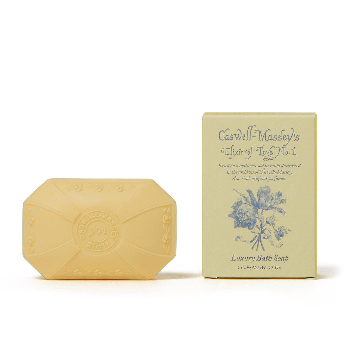 A bar of luxury Caswell - Massey Elixir of Love Bar Soap alongside its yellow packaging, decorated with vintage floral graphics and inscriptions marking it as "Caswell-Massey" and "est. 1815".