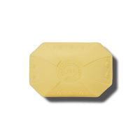 Hexagonal-shaped, pastel yellow, triple-milled soap bar with embossed decorative elements and the words "Caswell - Massey Elixir of Love" centrally displayed, on a plain white background.