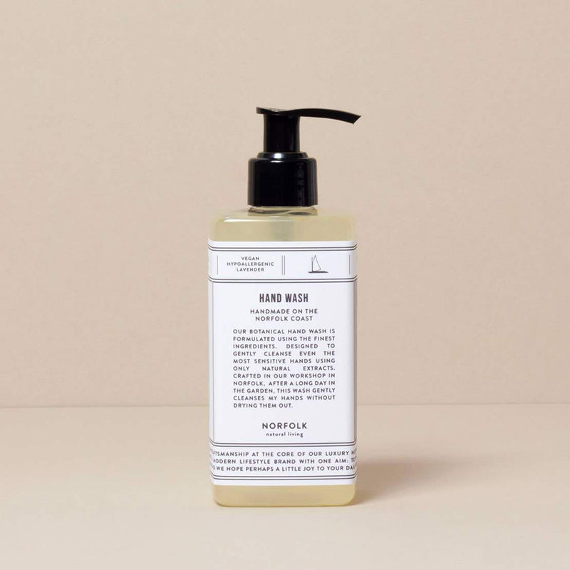 A Norfolk Natural Living Lavender Hand Wash bottle with a pump dispenser against a neutral beige background. The label features a minimalistic design with text describing the product's botanical extracts and origin in Norfolk.