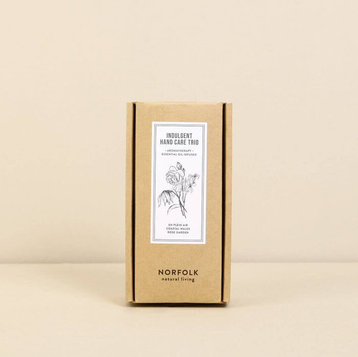 A cardboard box labeled "Hand care Trio - Coastal Walks, Rose Garden, En Plein Air" from Norfolk Natural Living, displayed against a neutral background, features elegant text and a botanical drawing inspired by the English countryside.