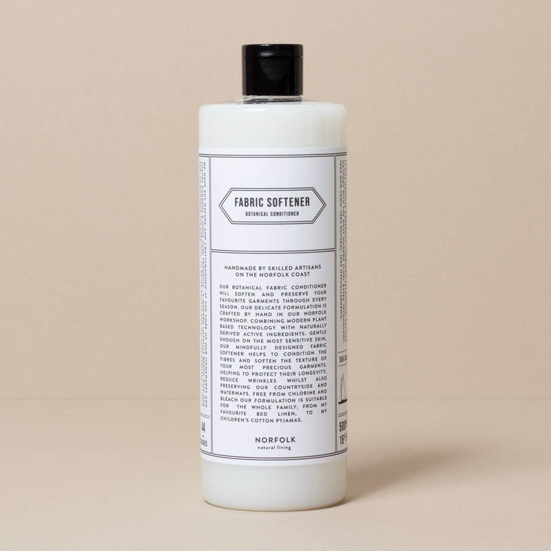 A large, white bottle of Norfolk Natural Living Coastal Fabric Conditioner with black text detailing the product's use and ingredients, set against a light beige background.