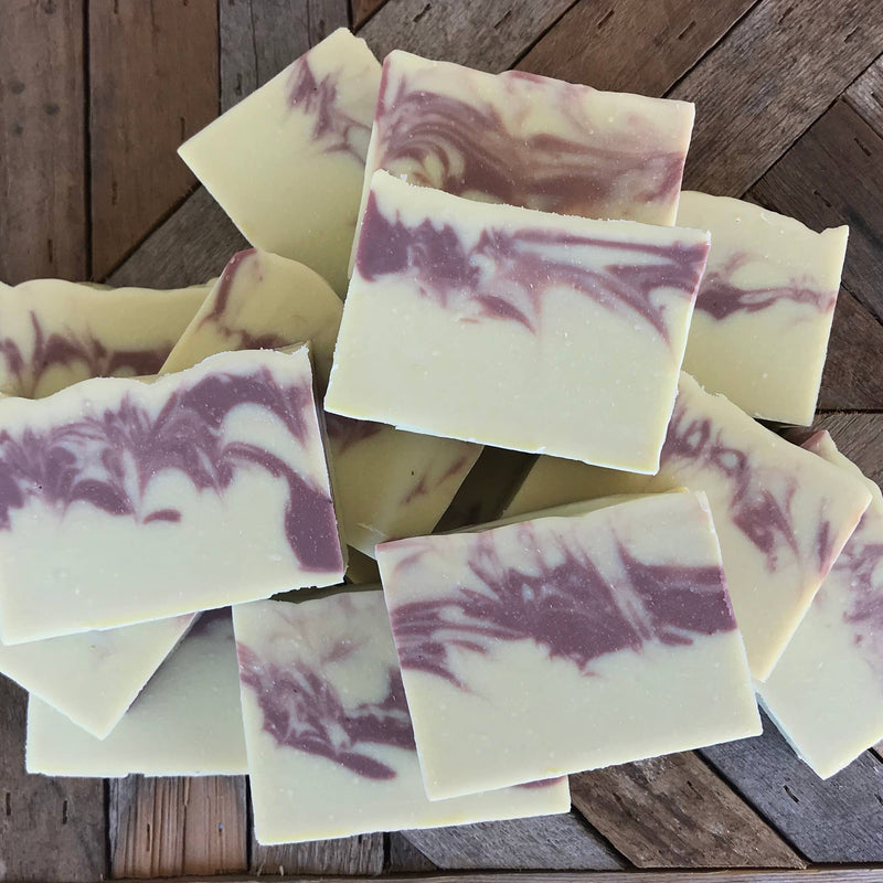Wild Botanicals - Honeysuckle Citrus Soap with swirled purple and white designs, infused with organic shea butter, displayed on a wooden surface.