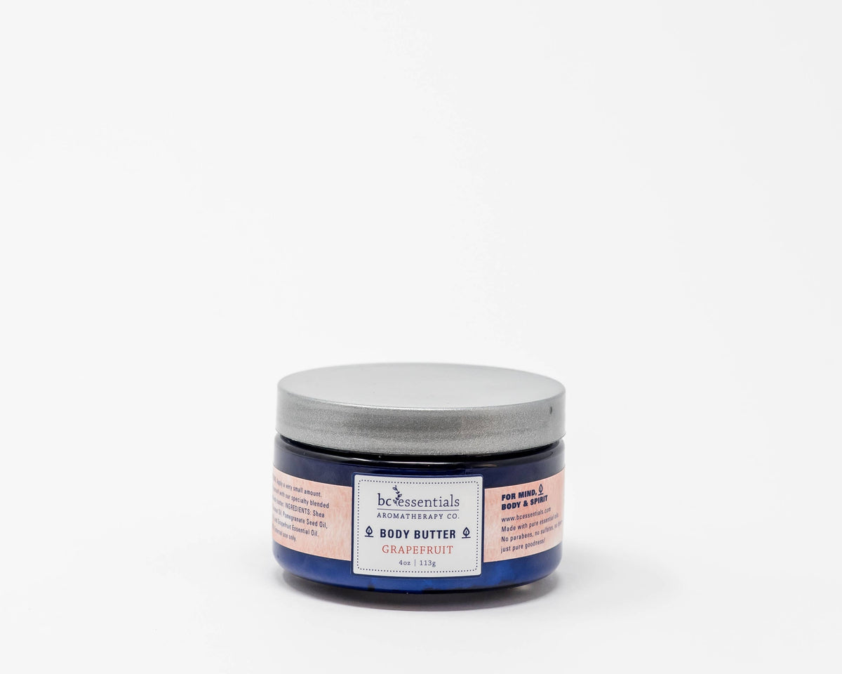 A container of BC Essentials - Invigorate Body Butter with organic coconut oil against a white background. The label is blue and white with visible product details.