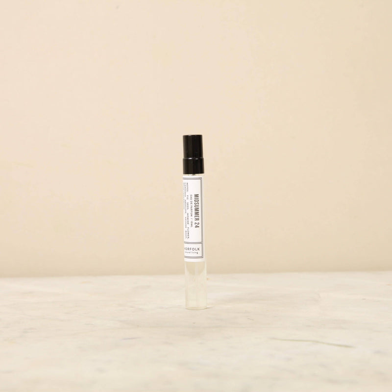 A Norfolk Natural Living Parfum - MidSummer 24 10ml spray bottle with a black cap on a light beige background, featuring minimalist label design and floral notes.