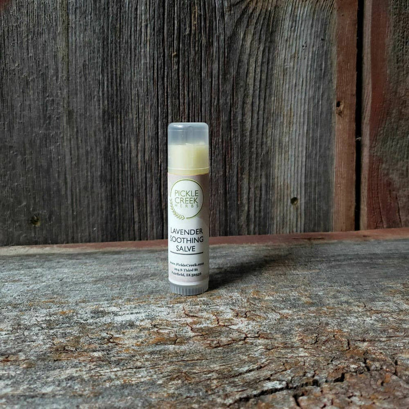 A tube of Pickle Creek Herbs Lavender Soothing Salve, .05 oz, formulated for eczema relief, on a rustic wooden surface against a weathered wooden backdrop.