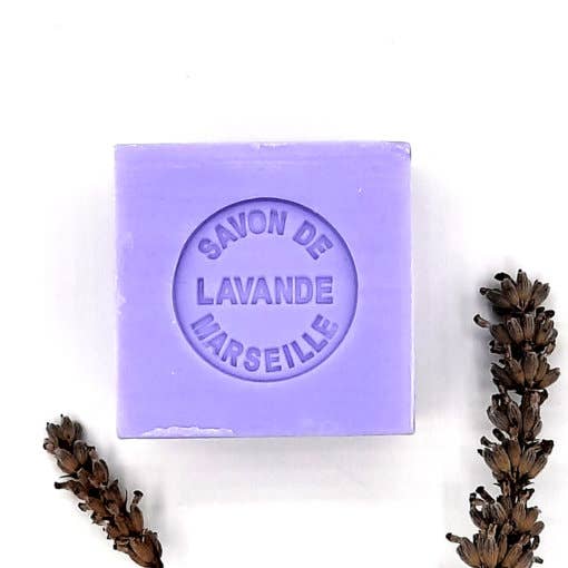 A purple bar of Senteurs De France Marseille Lavender Cube Soap labeled "savon de lavande" beside dried lavender sprigs on a white background.