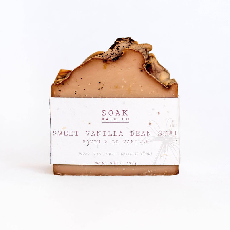 A SOAK Bath Co. - Sweet Vanilla Bean soap bar with a creamy brown top and a white label reading "soak bath co, sweet vanilla bean soap." The soap has textural details and sits against a white background.