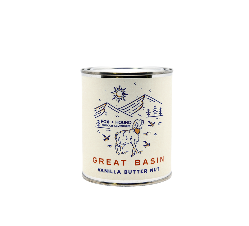 A can of Fox + Hound National Parks Great Basin Coffee - Vanilla Butter Nut with rustic wilderness illustrations including mountains, trees, a sun, and birds, labeled "National Parks Coffee." The can's background is white with a beige.
