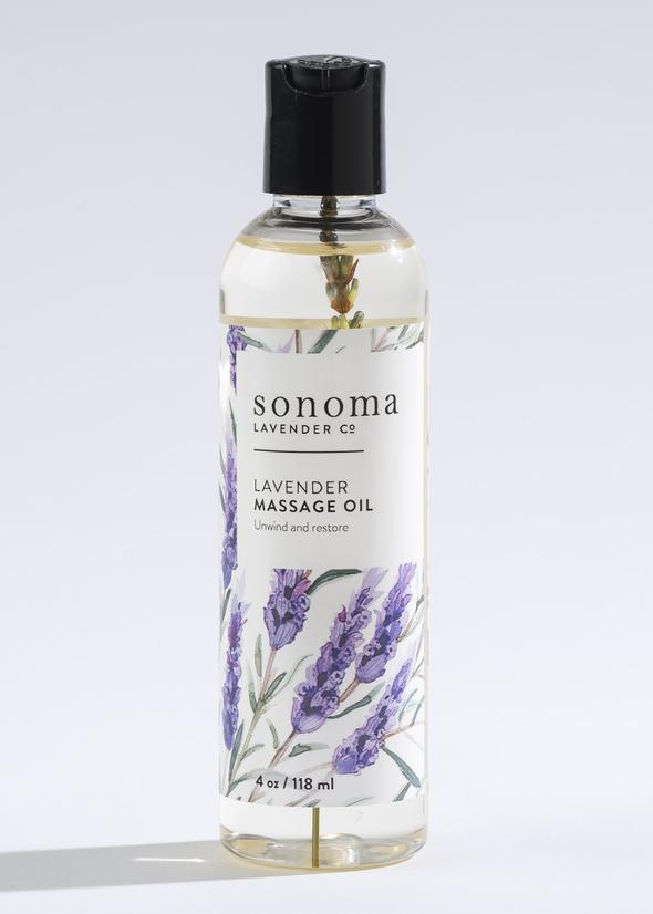 A clear bottle of Sonoma Lavender Massage Oil, labeled with lavender illustrations and text, against a light gray background. Enhanced with grapeseed oil.