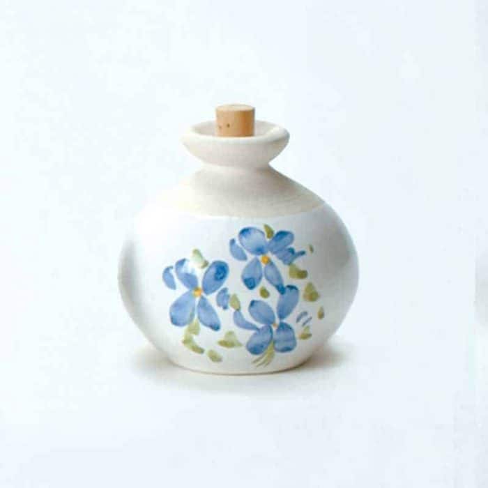 A La Lavande ceramic essential oil diffuser with a rounded body and a wooden cork, adorned with hand-painted blue flowers on a white background.
