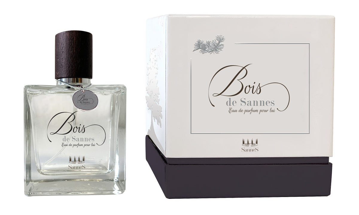 A clear glass perfume bottle labeled "Chateau De Sannes - Bois de Sannes Eau de Parfum Pour Lui" next to its elegant white packaging box with gray accents and stylized text.