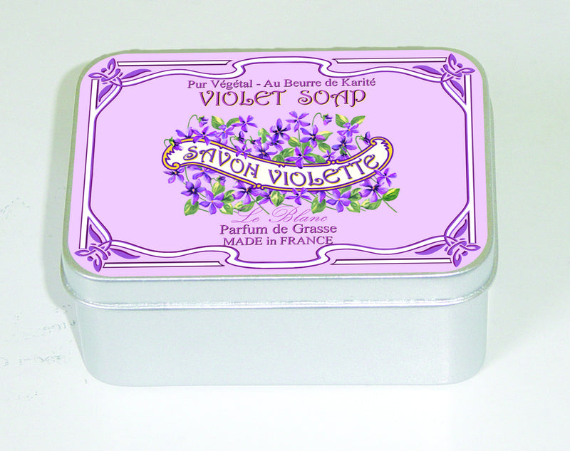 A tin container with a decorative label for "Le Blanc Violet 100gm Soap Tin" from Le Blanc Made in France, featuring elegant purple floral designs and French text, illustrating its origin and ingredients.