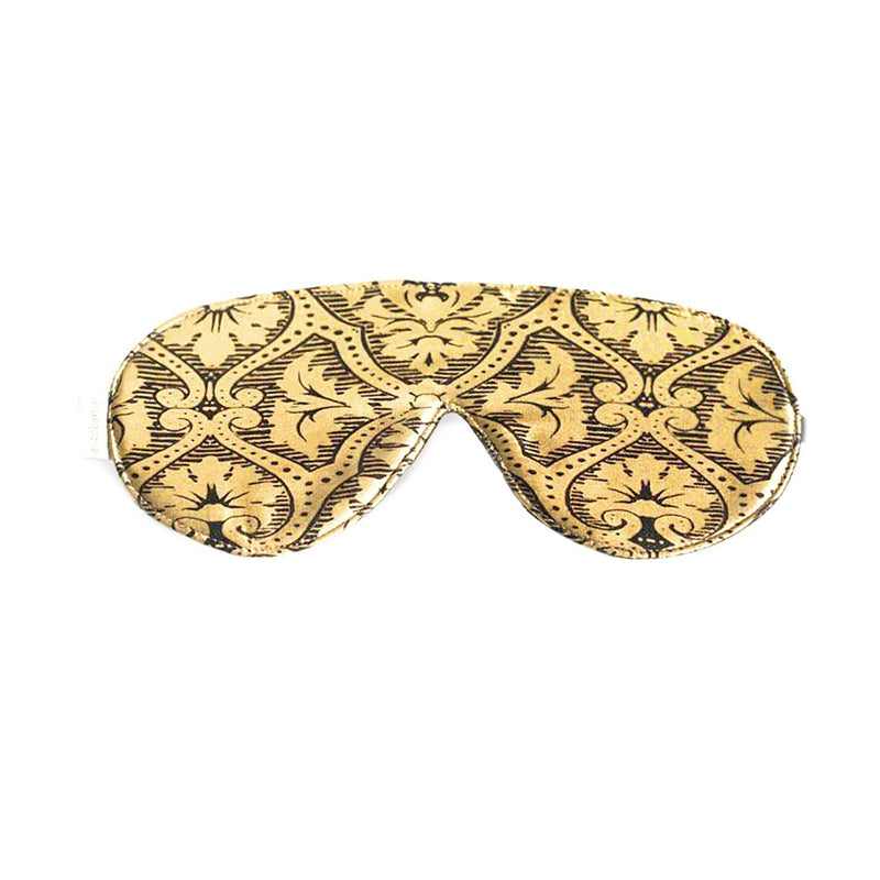 A decorative Elizabeth W silk sleep mask with an intricate gold and black pattern on a white background.
