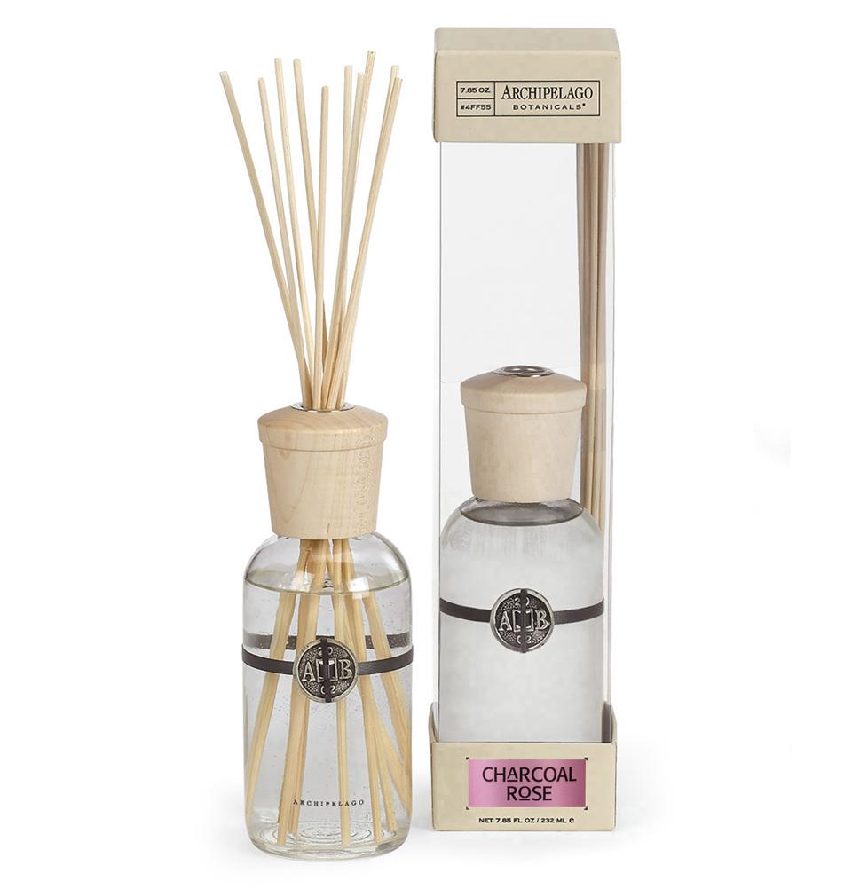 A reed diffuser set labeled "Archipelago Charcoal Rose", featuring a glass bottle with liquid and multiple reed sticks, alongside its packaging.