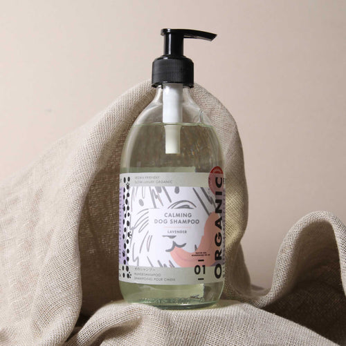 A bottle of Made & Sent Calming Dog Shampoo 500ml with lavender scent, displayed on a beige cloth against a neutral background. The label features modern fonts and designs.