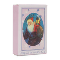 A bar of Victoria Scandinavian Merry Christmas Soap in pale pink packaging, featuring a vintage illustration of Santa Claus holding a lantern, surrounded by blue stars. The text "God Jul" and the soap weight "1.