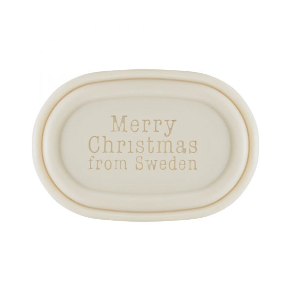 An oval-shaped, cream-colored ceramic dish with the embossed message "merry Christmas from Sweden" centered on it, presented on a plain white background. This is perfect for displaying your Victoria Scandinavian Merry Christmas Soap - Elf with Presents from Victloria Scandinavian Soaps.