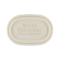 A beige oval-shaped scented soap with the embossed words "Victoria Scandinavian Merry Christmas Soap - Santa with Lantern" centered on its surface by Victoria Scandinavian Soaps.