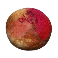 A textured, spherical object with blended hues of red and beige fibers, creating a mottled, tactile appearance. This Fiat Luxe - Cinnamon Oat felted soap incorporates essential oils for added benefits.