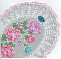 A decorative cotton batiste Vintage-Inspired Hanky - Clover-Shaped Mum Hanky by Hankies ala Carte with a floral design featuring pink peonies and smaller blue and purple flowers, set against a white lace-patterned background. A circular blue sticker reads