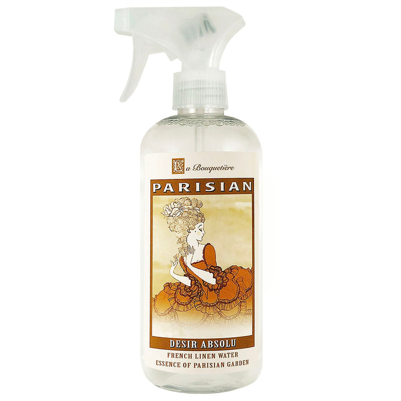 A spray bottle labeled "La Bouquetiere Desir Absolu Linen Water with essential oils, essence of parisian garden" by La Bouquetiere, featuring a vintage-style illustration of a woman surrounded.
