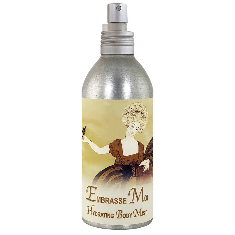 A cylindrical silver spray bottle of La Bouquetiere Embrasse Moi Body Mist featuring a vintage illustration of a woman in a brown dress with a white wig on a beige background, now crafted with alcohol-free