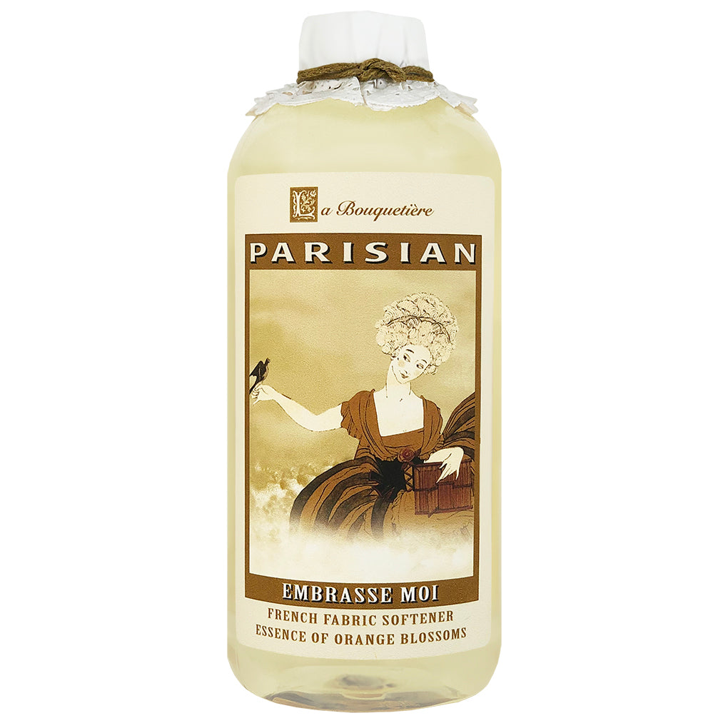 A bottle of La Bouquetiere Embrasse Moi Fabric Softener featuring a vintage style label with an illustration of an 18th-century woman.