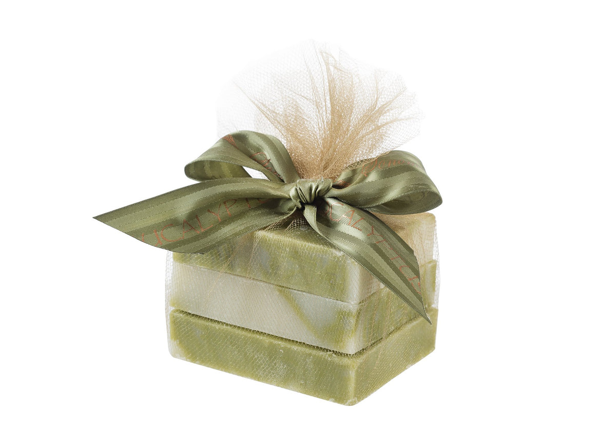 A square gift box wrapped in translucent gold fabric and tied with an olive green ribbon that has red text, all set against a white background, encasing Sonoma Lavender's Eucalyptus Trio of Eucalyptus Soap - 3 -4oz bars.