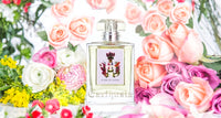 A bottle of Carthusia Fiori di Capri Eau de Parfum by Carthusia I Profumi de Capri surrounded by a colorful arrangement of pink, white, and yellow flowers, with roses being prominent.