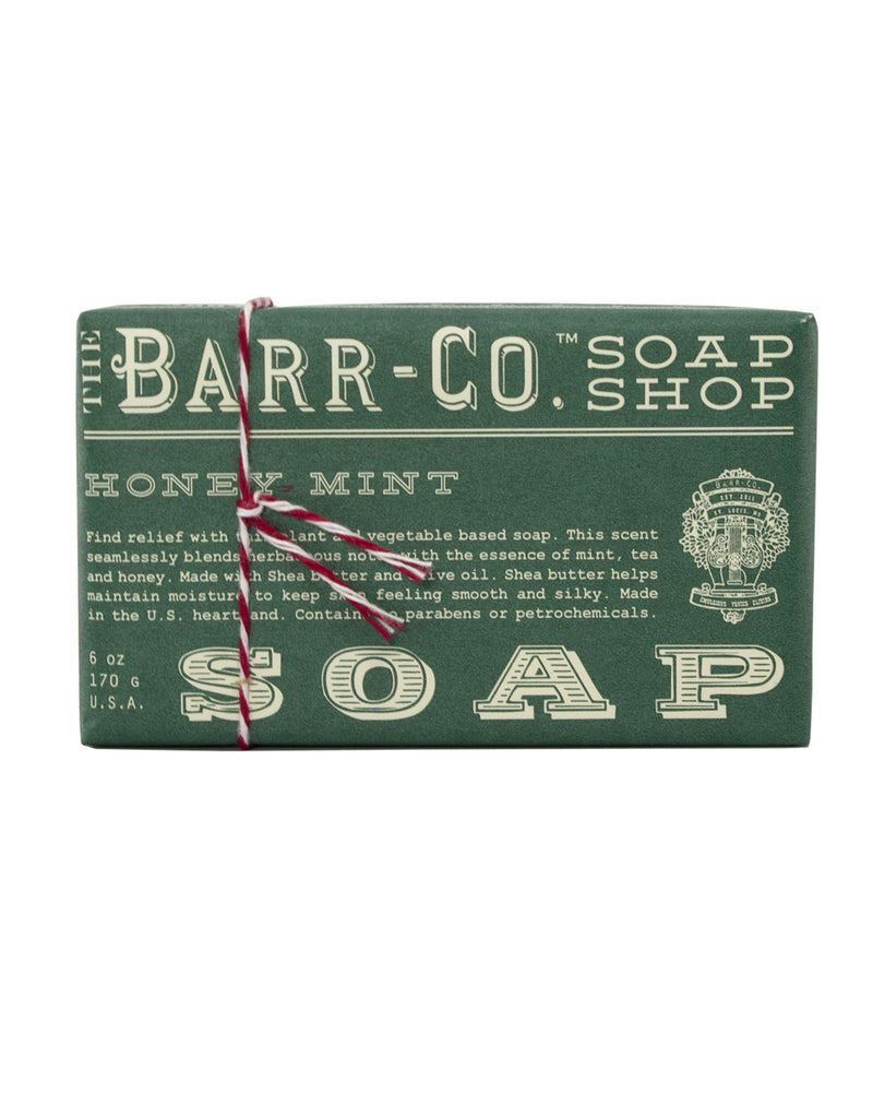 A bar of Barr-Co. Honey Mint Triple Milled Bar Soap tied with a red and white string, featuring a label that describes the product as a mint-scented, handmade, triple milled vegetable soap.