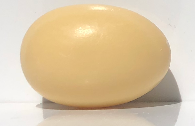 A single oval-shaped, smooth, yellow, triple-milled La Lavande Egg Soap - Honey Linden bar placed against a white background with a soft shadow beneath it.