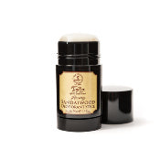 A small, elegant black and gold container of Taylor of Old Bond Street Sandalwood Luxury Deodorant Stick with its lid removed, displayed against a plain white background.