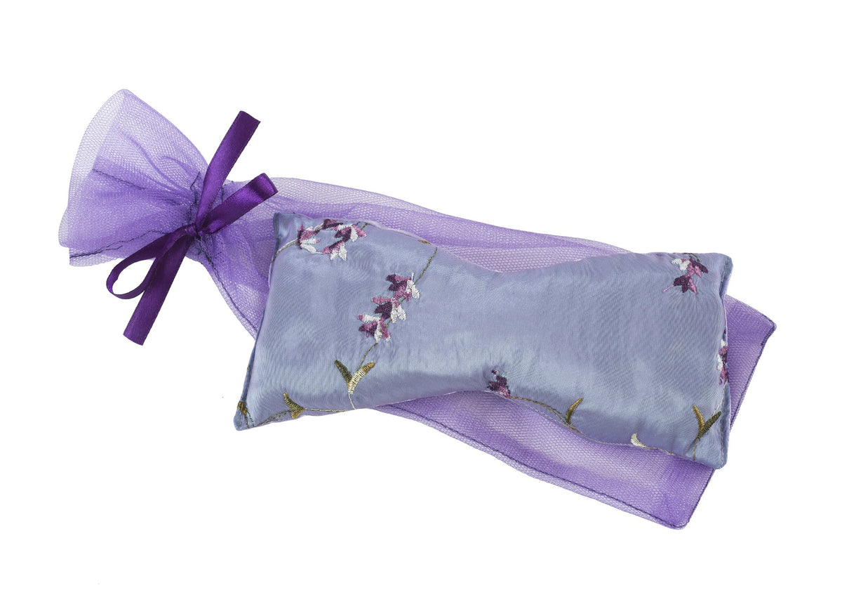 A Sonoma Lavender Eye Pillow - Embroidered Lavender, nestled inside a translucent purple drawstring bag, isolated on a white background.