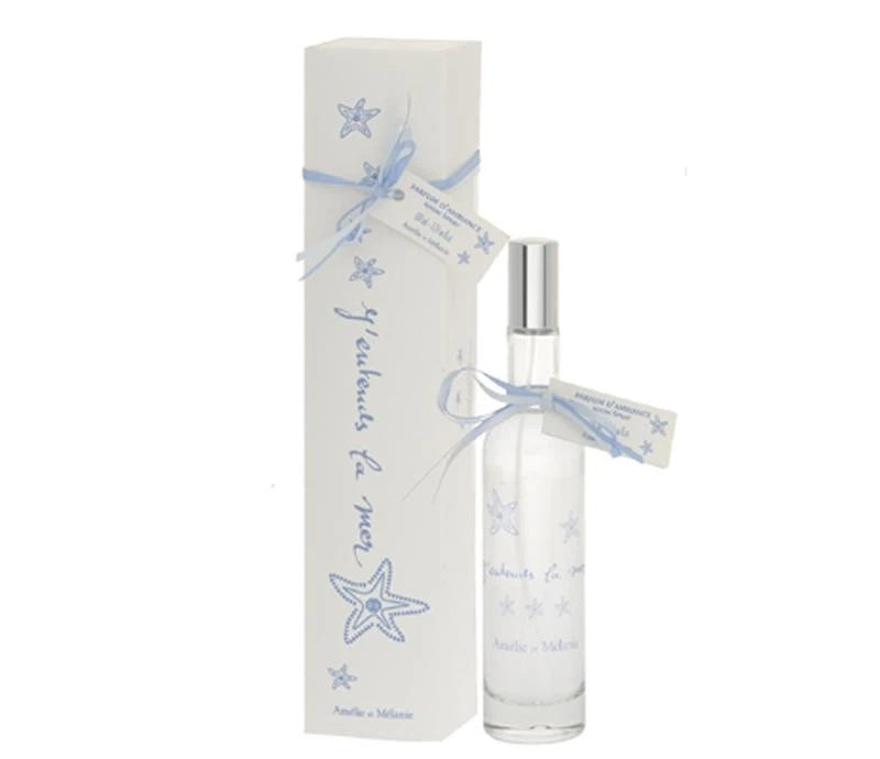 A Lothantique room spray bottle with a silver cap and clear body alongside its white rectangular packaging adorned with blue stars and ribbons. The label reads "étoiles de mer" for the Amelie et Melanie J'Entends la Mer Room Spray.