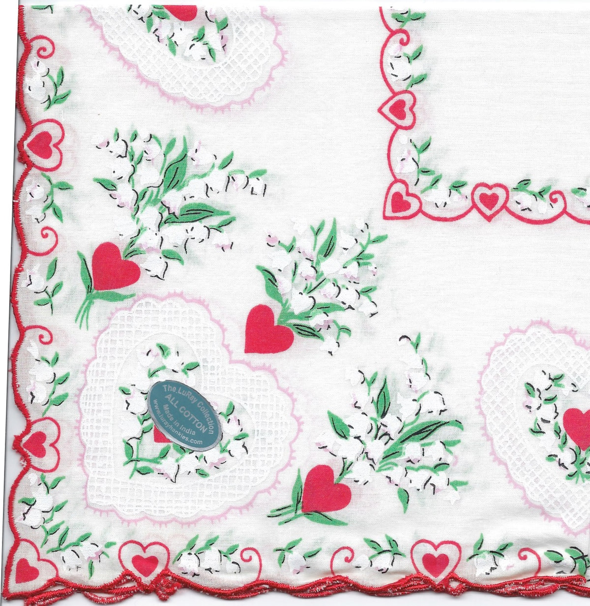 A close-up of a Vintage-Inspired Hanky - Lacey Heart Corner with Lily of the Valley napkin from Hankies ala Carte, crafted with a romantic floral and heart design featuring delicate green vines, red hearts, and white lace patterns, with a "true love" sticker in.