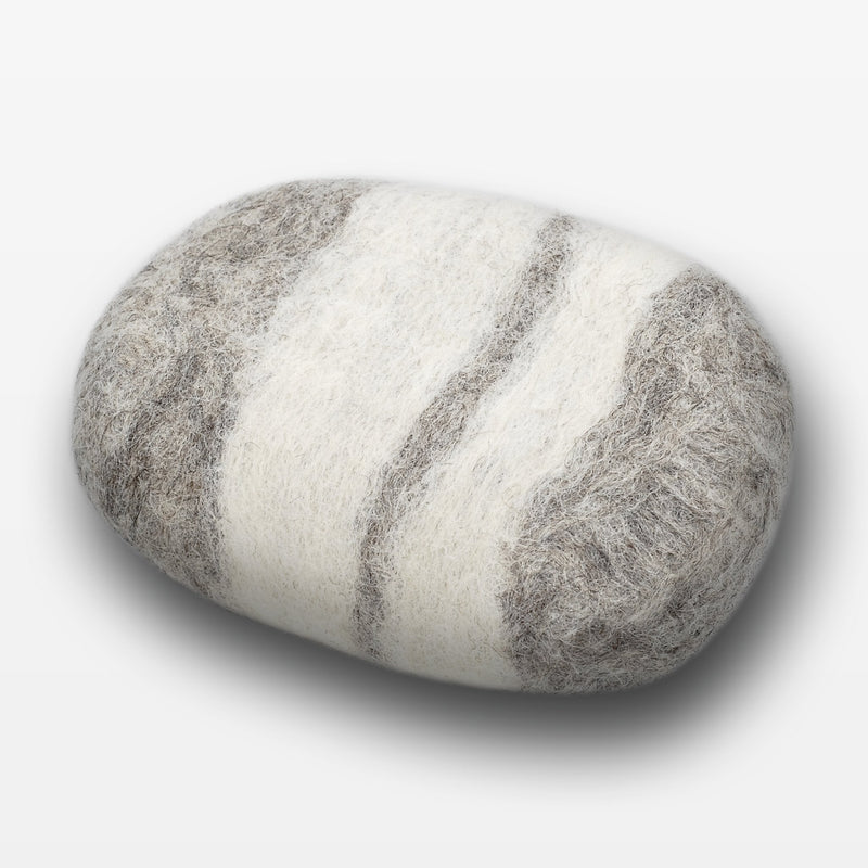 A smooth, oval stone painted with alternating horizontal stripes in shades of gray and white, placed on a Fiat Luxe - Striped Lavender Felted Soap - Gray background.